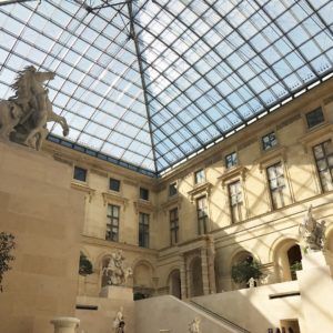 Grand courtyard beneath a glass سق roof in a historic museum with stone walls and statues