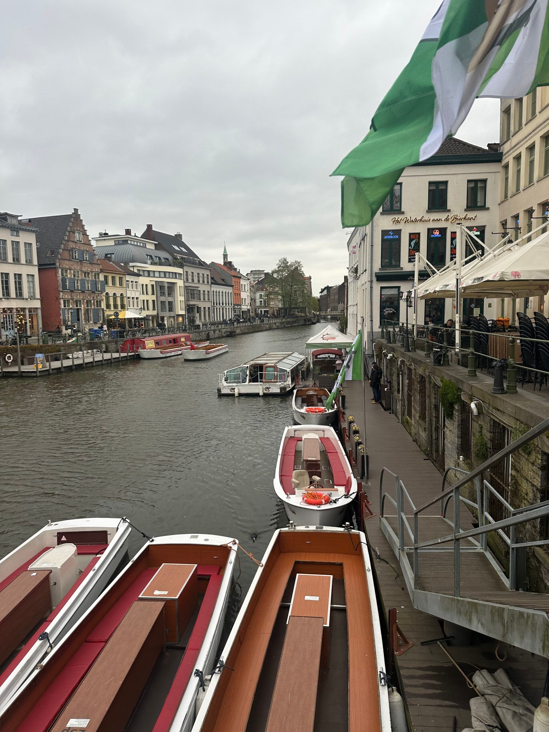 Canal with moored boats beside old buildings under a cloudy sky