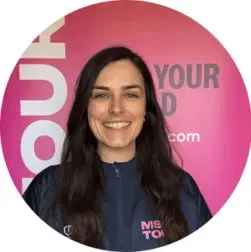 Smiling woman in a dark jacket in front of a pink branded backdrop