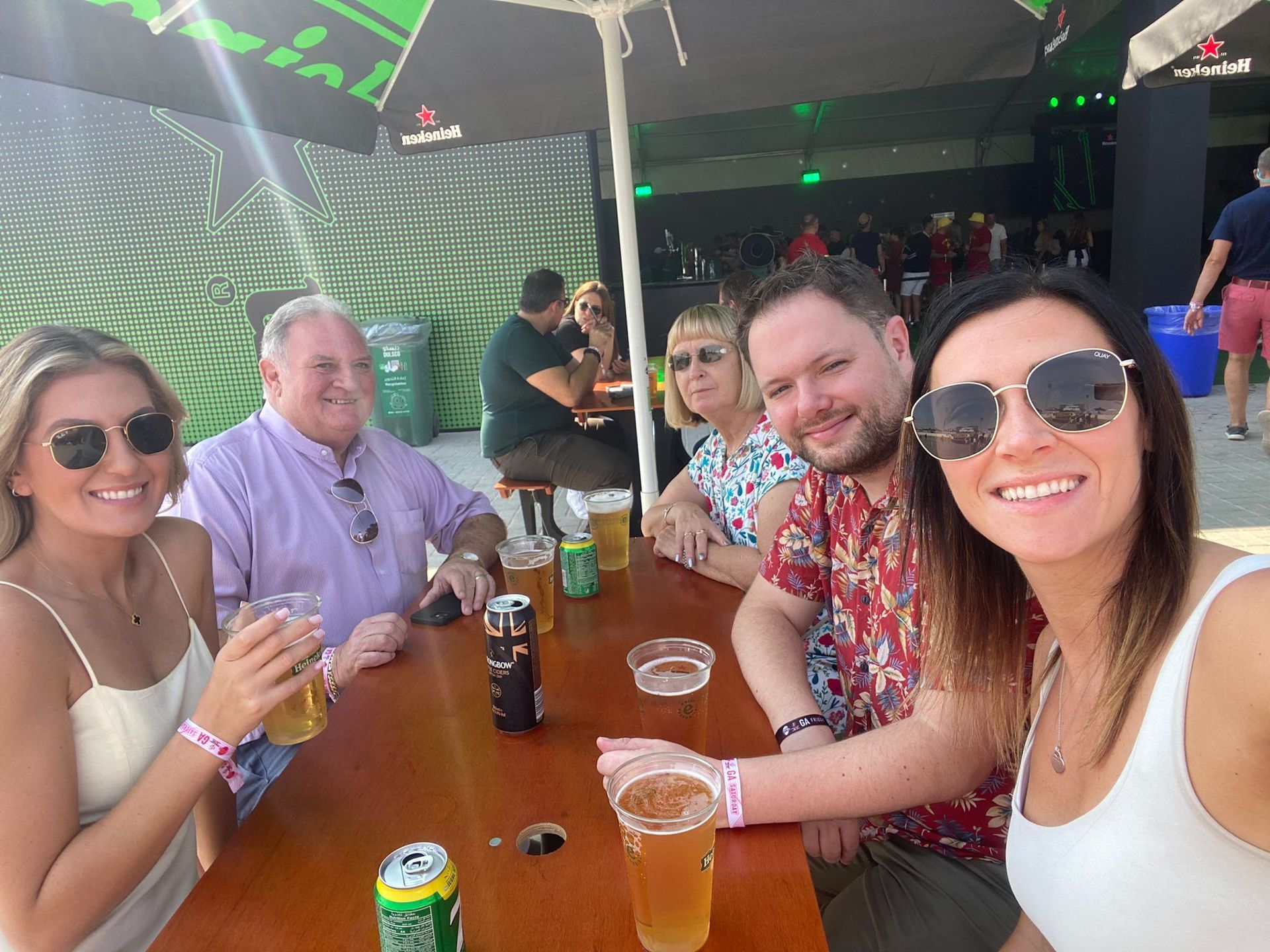 Four people smiling at a bar table with drinks in an outdoor covered venue