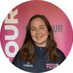Smiling person in a navy jacket before a pink MSQ Tour backdrop