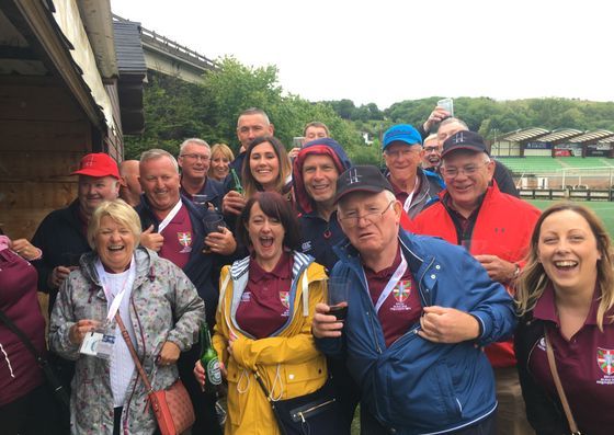 Smiling group in rain jackets posing outdoors under a bridge