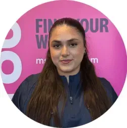 Woman in a navy jacket posing before a pink promotional backdrop