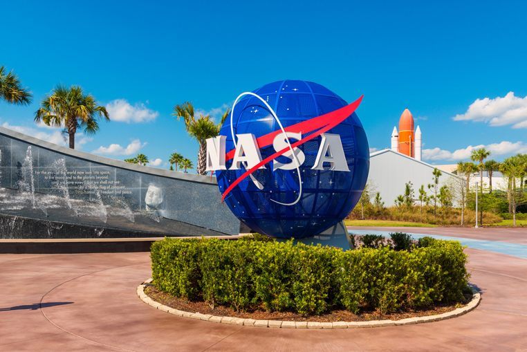 NASA globe sign outside a space center, with palm trees and blue sky