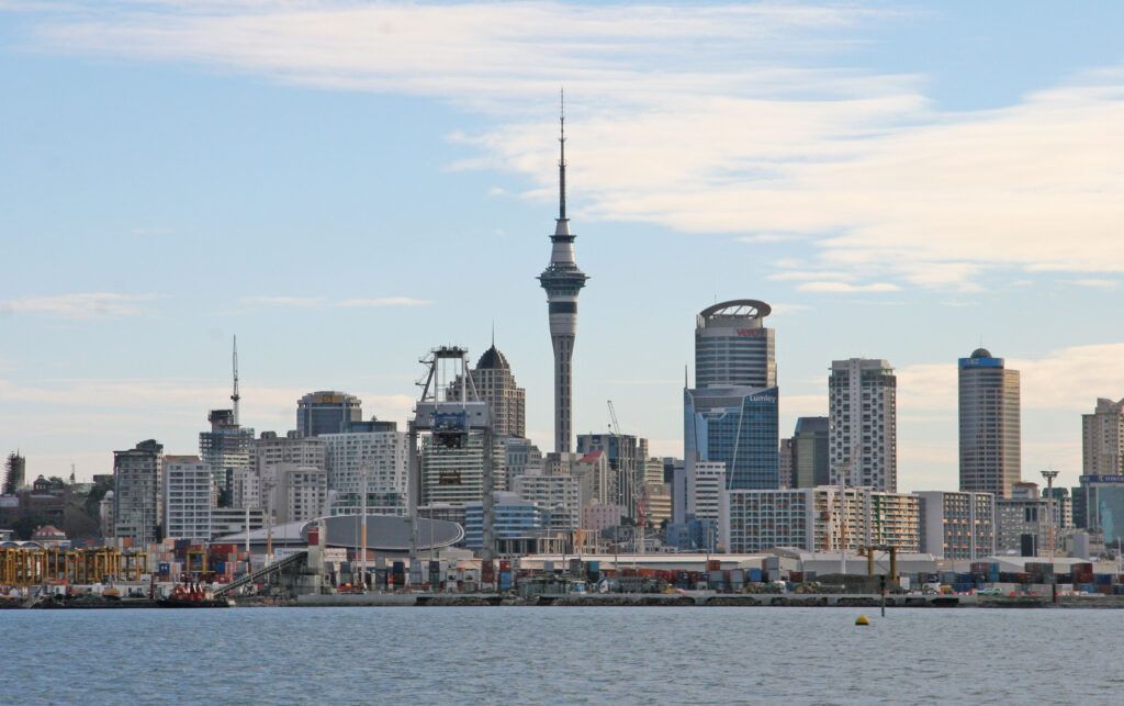 Auckland skyline with Sky Tower under a blue sky, seen across the waterfront.