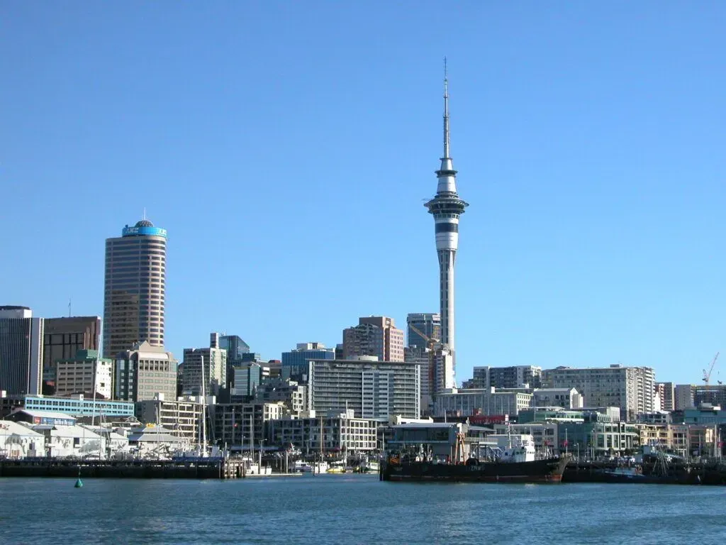 City skyline with a tall tower and waterfront under a clear blue sky