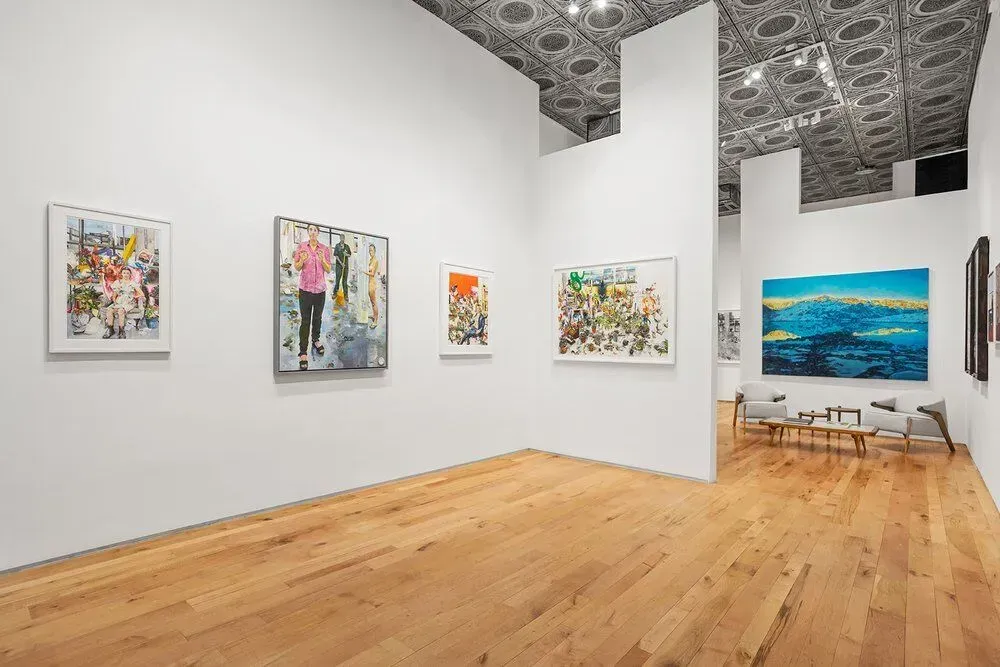 Bright art gallery with paintings on white walls and wood floors, including a large blue seascape.