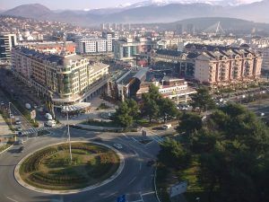 Aerial view of a city roundabout with surrounding apartment buildings and distant mountains.