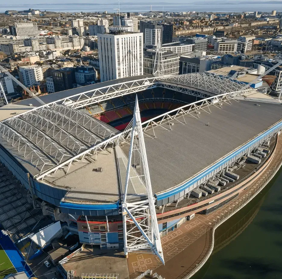 Aerial view of a modern stadium with a white roof and waterfront setting in a city.