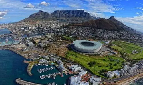Aerial view of Cape Town’s stadium, harbor, and Table Mountain under a blue sky