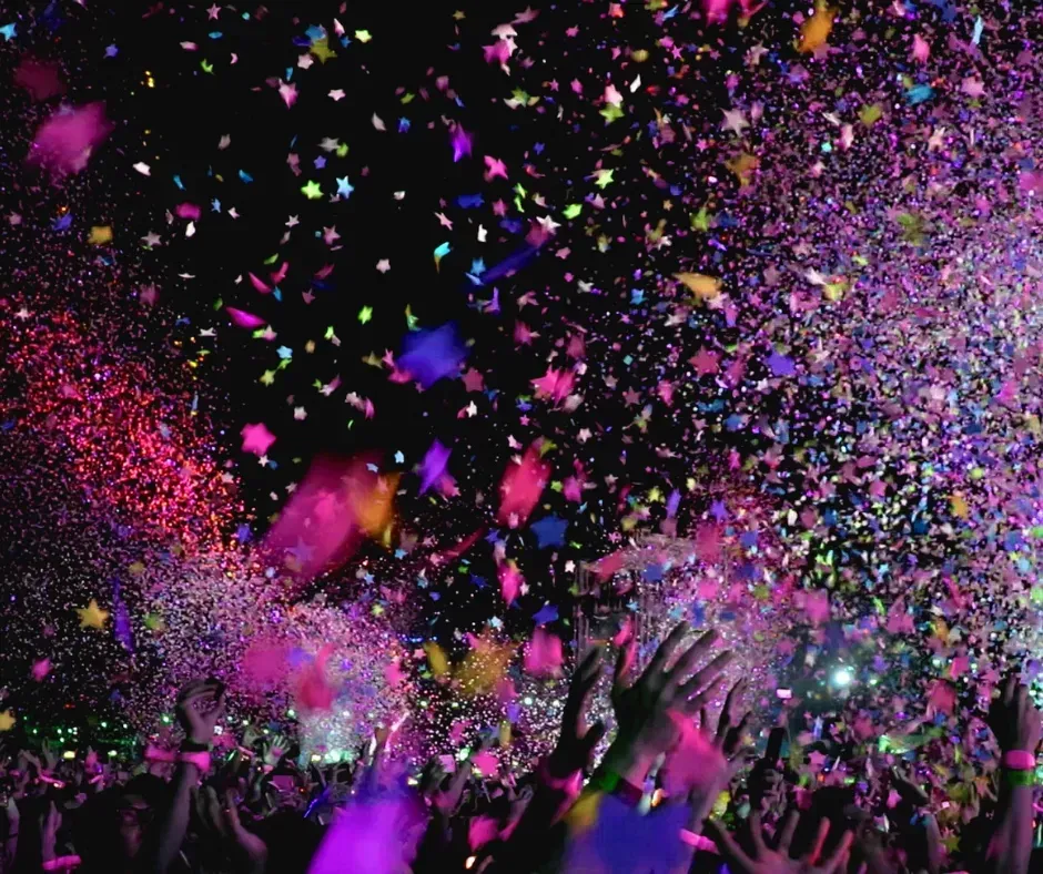 Colorful confetti bursts over a cheering crowd at a nighttime celebration