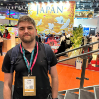 Man standing at a Japan expo booth with orange flooring and a large “JAPAN” sign in the background