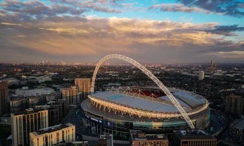 Sunset aerial view of Wembley Stadium with its white arch over London skyline