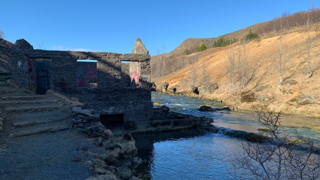 Stone ruins beside a blue river in a rocky canyon under clear daylight