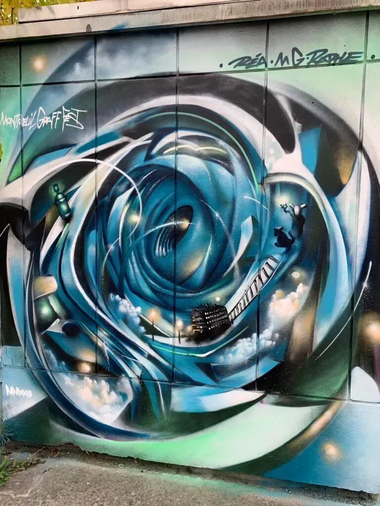 Blue and silver abstract graffiti mural with swirling vortex shapes on a wall
