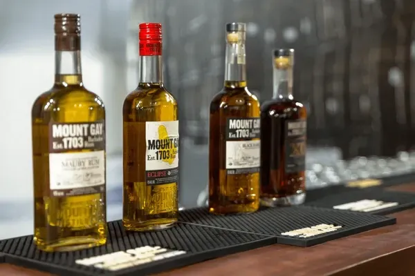 Four whiskey bottles with red and gold caps on a bar counter