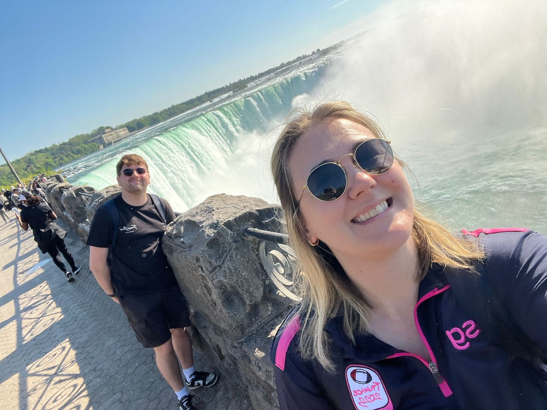 Two people posing by Niagara Falls beside the rushing water and mist