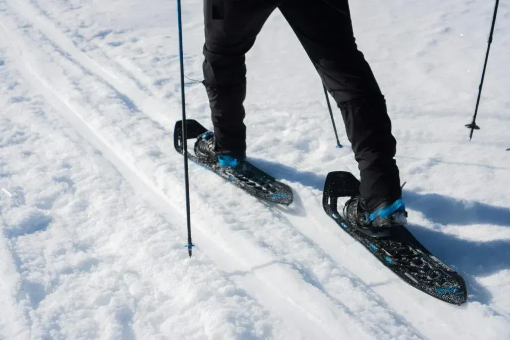 Close-up of a skier’s black boots and skis gliding over snow on a slope