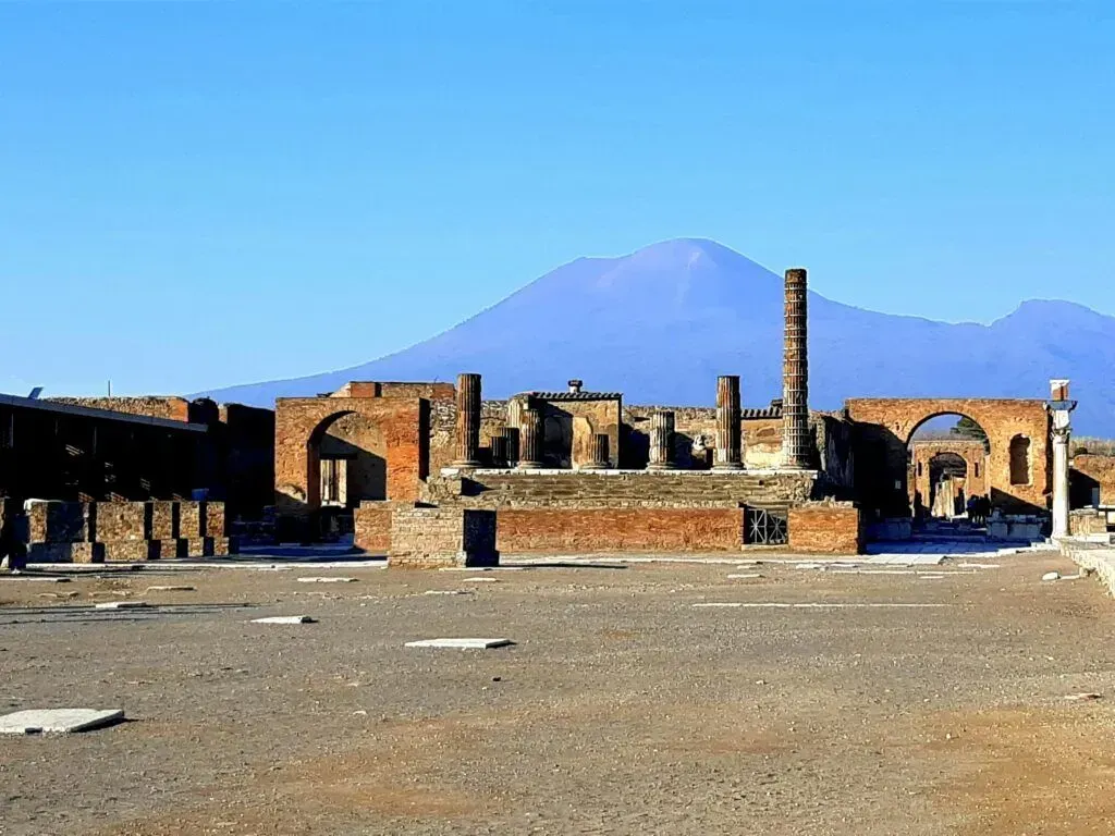 Ruins of a desert settlement with mountains in the background under a clear blue sky