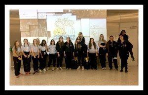 Group of people standing in a hall in front of a presentation screen, posing for a photo