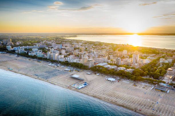 Aerial view of a beach town at sunrise, with shoreline, buildings, and calm water.
