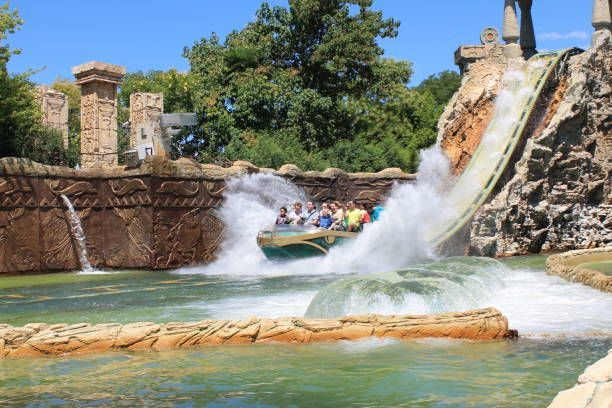 Rafting boat plunging through a rocky water slide with spray at an amusement park