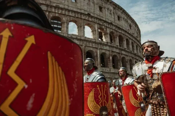 Roman soldiers in red shields stand before the Colosseum