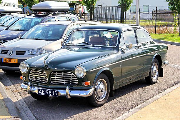 Classic green sedan parked on a sunny street beside other cars