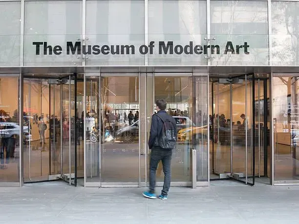 Entrance to The Museum of Modern Art with a person standing at the glass doors