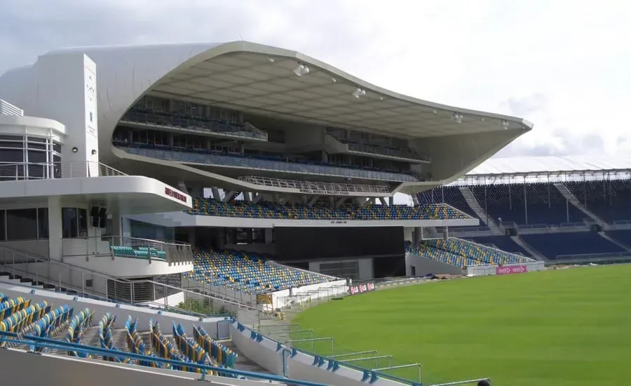 Empty modern stadium with covered seating and green field, viewed from the stands