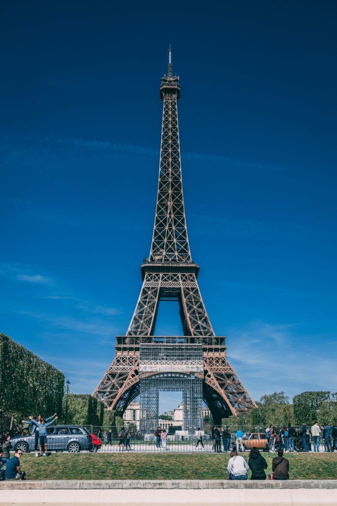 Eiffel Tower under a clear blue sky with people and trees in the foreground