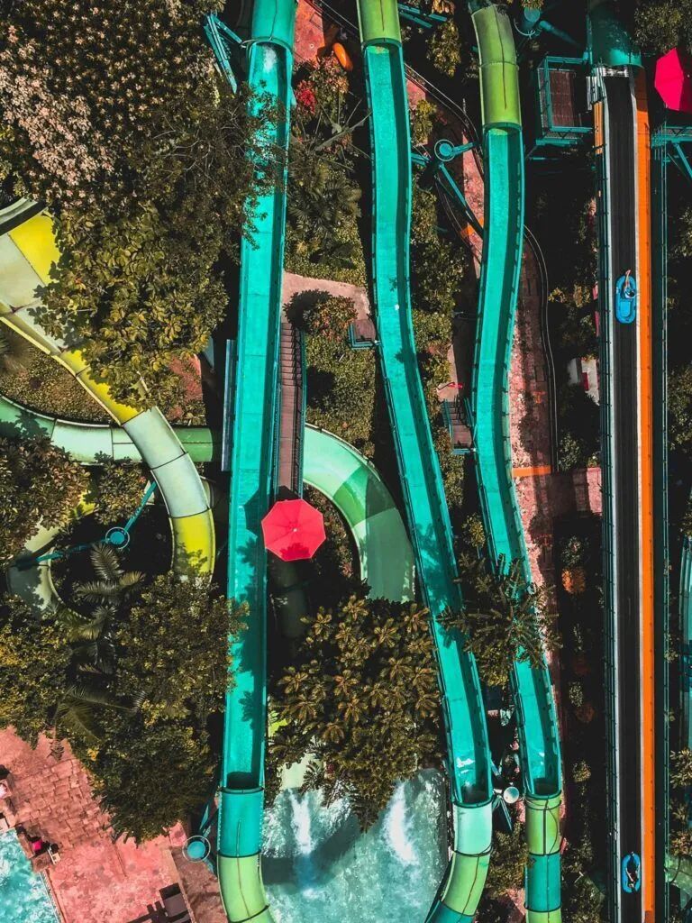 Aerial view of colorful curved water slides and a red umbrella-like canopy in a water park