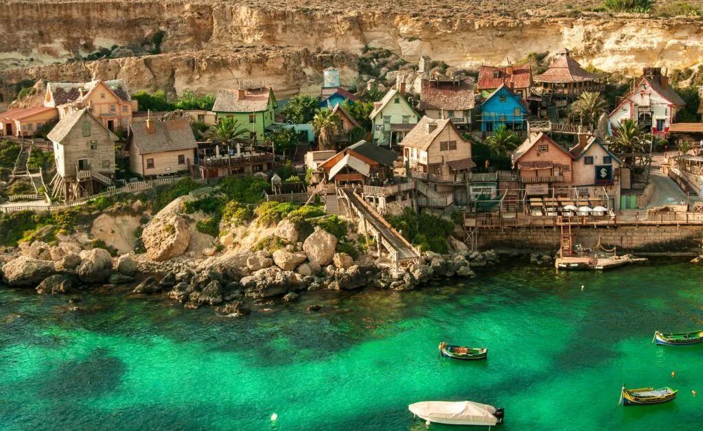 Cliffside coastal village with colorful houses above turquoise water and small boats