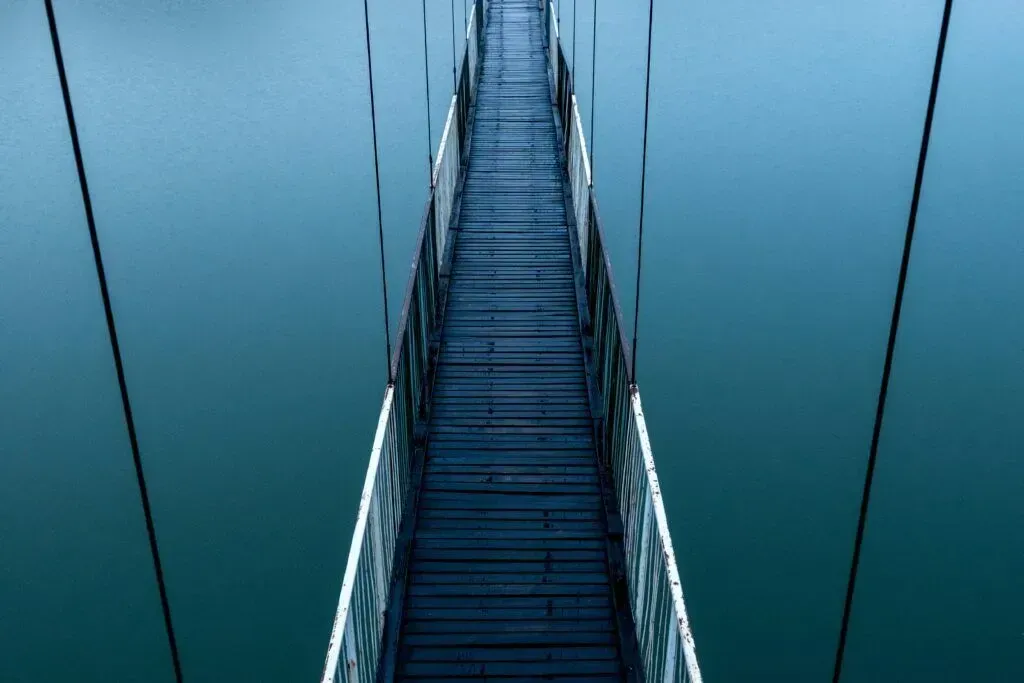 Narrow metal staircase ascending between blue walls, viewed from below.