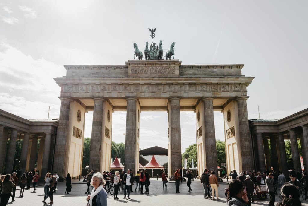 People walking in front of the Brandenburg Gate in Berlin on a cloudy day