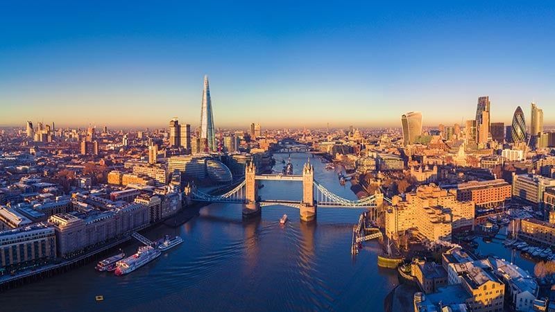 Aerial view of Tower Bridge and the Thames at sunset, with London skyline and the Shard in warm light