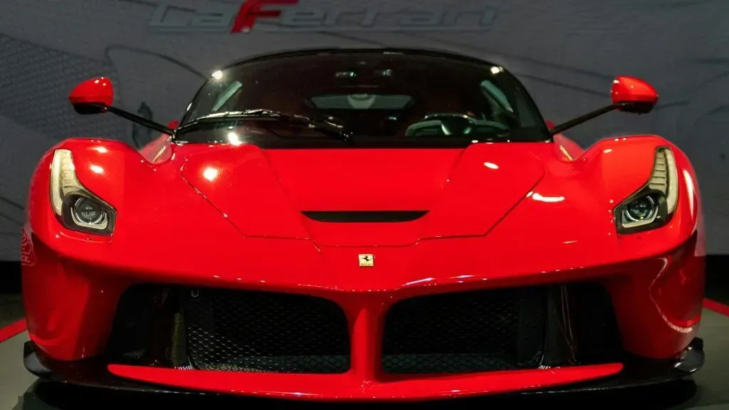 Front view of a red sports car in a showroom, with headlights on and black grille details