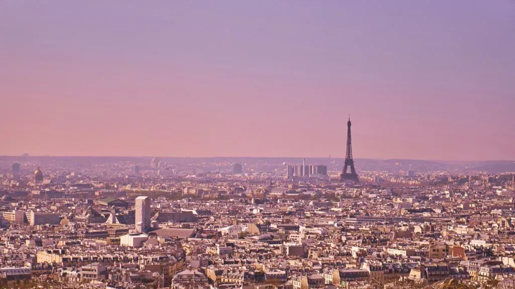 Paris skyline at sunset with the Eiffel Tower in the distance under a pink sky