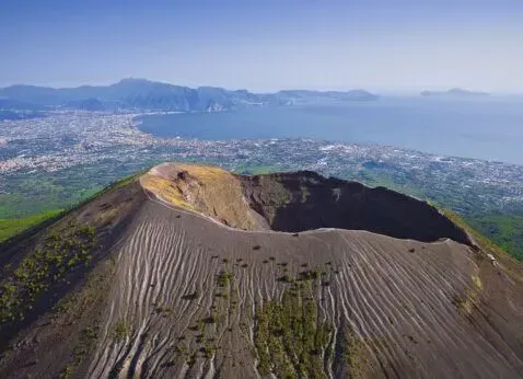 Volcanic crater overlooking a city and coastline under a clear blue sky