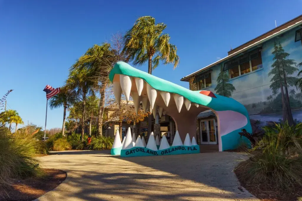 Colorful dolphin-shaped building entrance with palm trees and mural in bright daylight