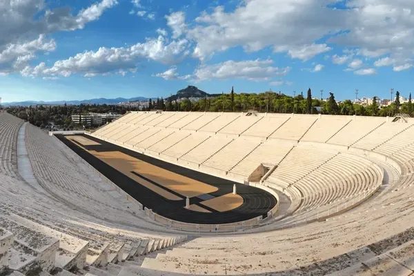 Ancient open-air stadium with white stone seats under a blue sky and clouds