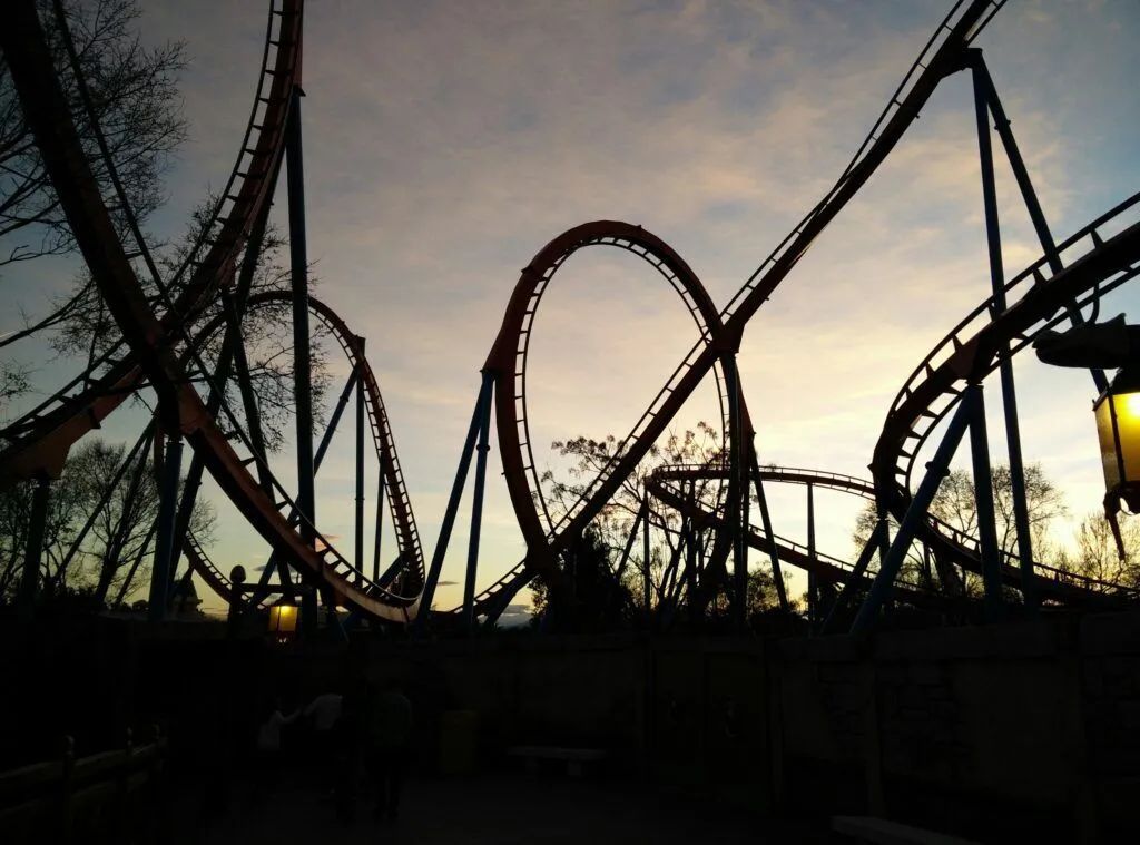 Silhouetted roller coaster loops and tracks at dusk against a fading sky