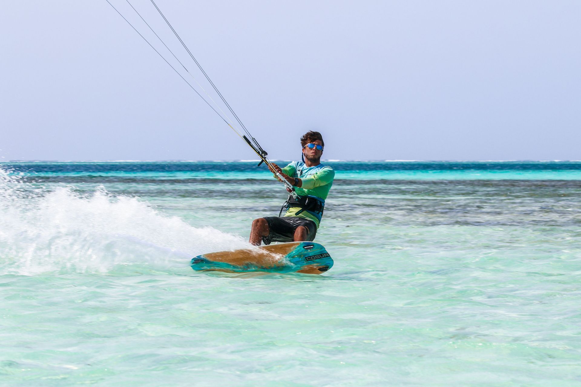 Kitesurfer riding over turquoise water with a kite sail in a sunny lagoon