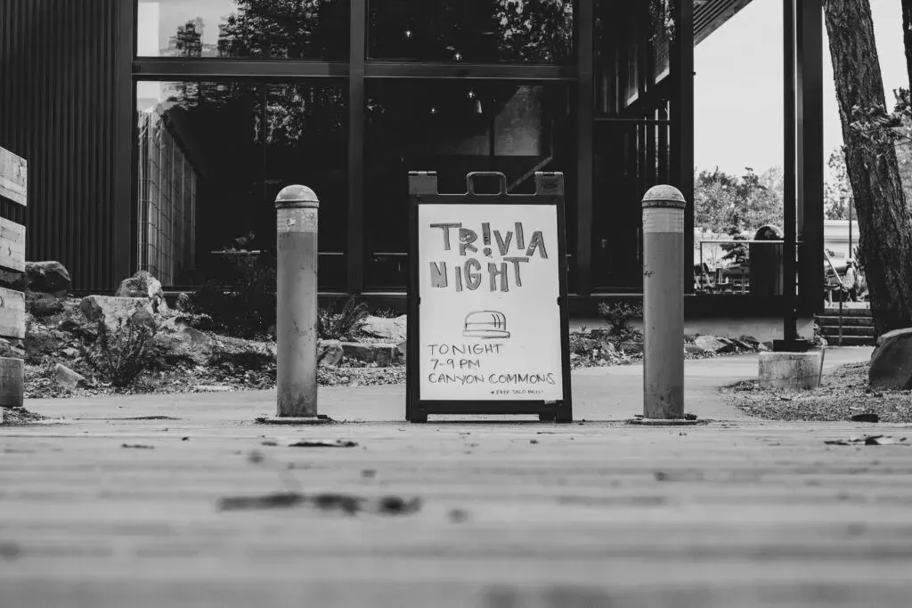 Black-and-white sign reading “TRASH NIGHT” on a sidewalk between two bollards