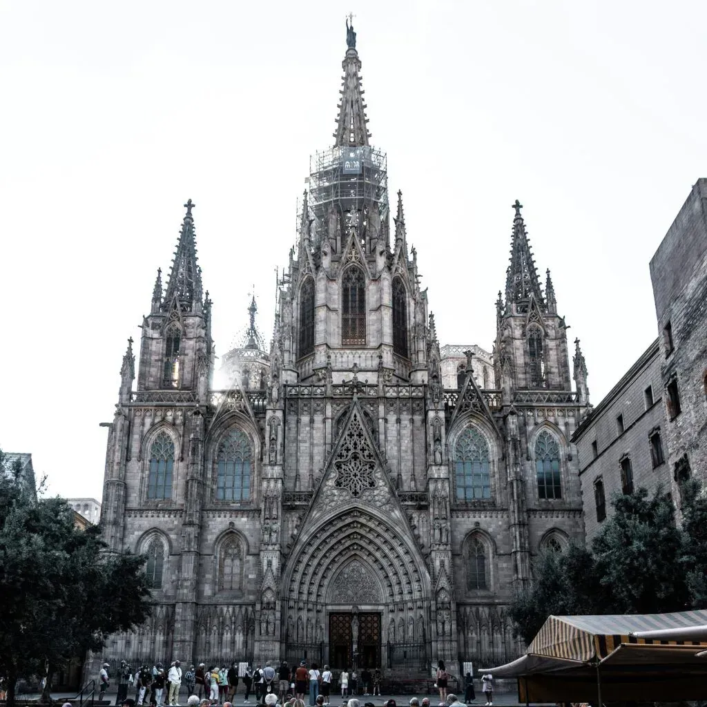 Gothic cathedral façade with three spires and ornate archway in a city square