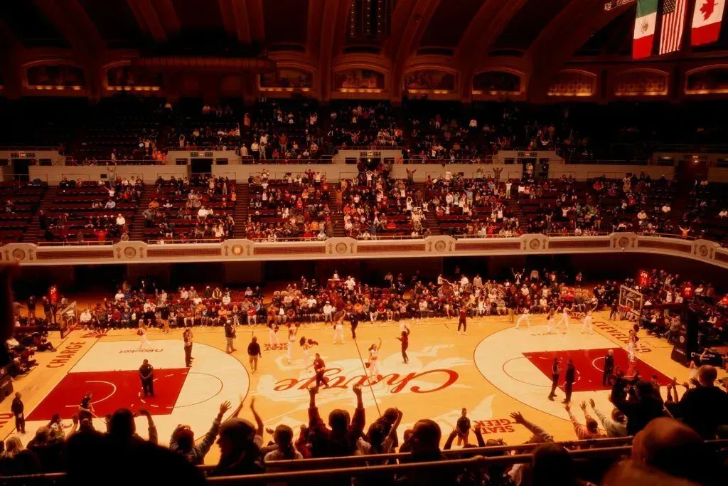 Indoor basketball game in a packed arena, with players on the court and fans in the stands