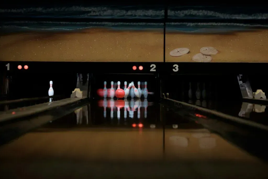 Bowling alley lane with pins lit at the far end and polished floor reflections
