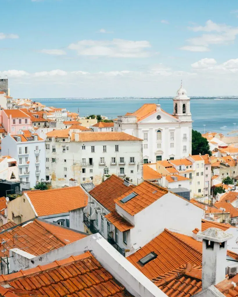 Whitewashed coastal town with red-tiled roofs overlooking a blue sea and harbor