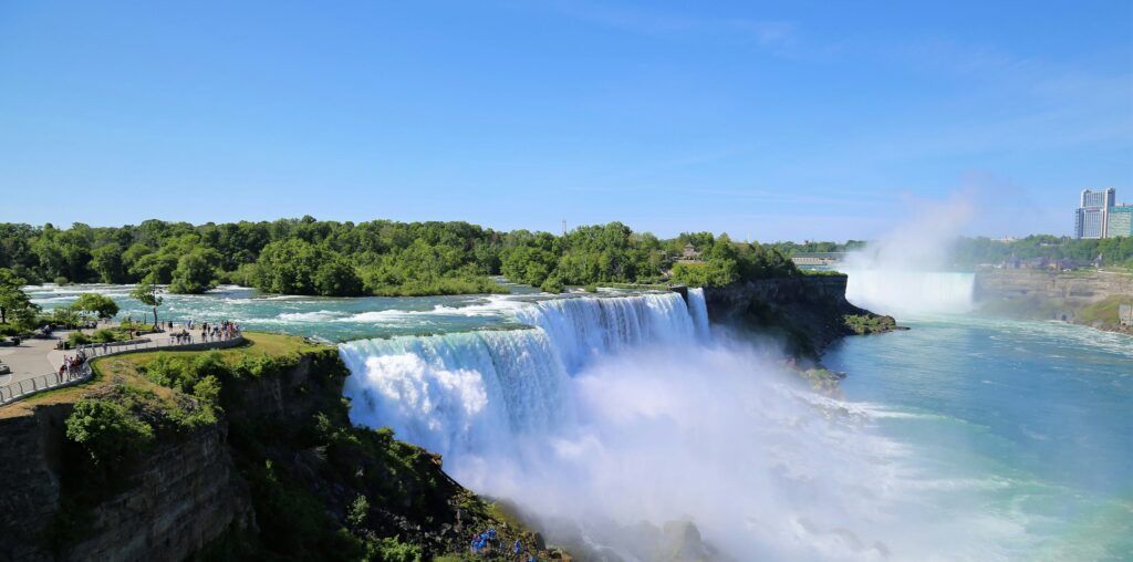 Niagara Falls with powerful white water cascading over cliffs under a clear blue sky