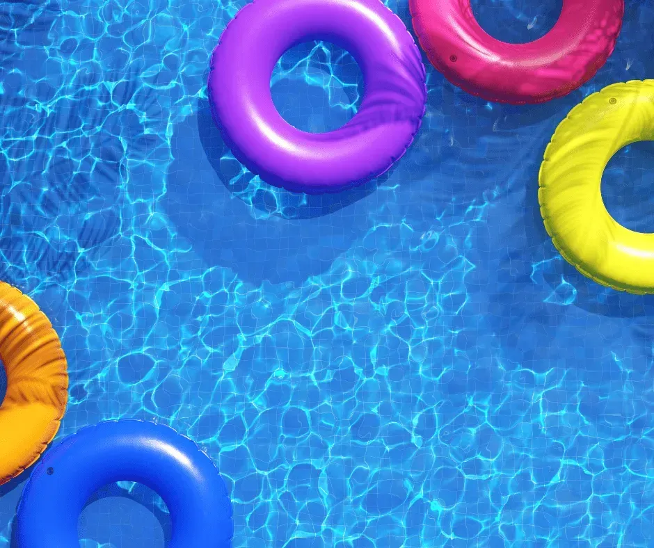 Colorful inflatable pool rings floating on bright blue water